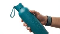 Hand holding turquoise water bottle with wrist strap against white background. Hydration concept for fitness, sports and healthy lifestyle activities.