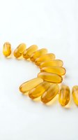 Golden omega-3 fish oil capsules arranged in a curved line on white background, representing dietary supplements, wellness, nutrition, and health supplementation.