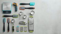 Modern kitchen utensils and tools collection arranged on white background, featuring colorful silicone handles and stainless steel accessories for cooking.