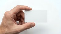 Male hand holding blank white business card mockup against clean background for branding and corporate identity design projects.