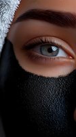 Close-up view of expressive blue eye with defined eyebrow and long eyelashes, partially covered by black face mask, showing contemporary protective wear.