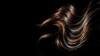 Flowing brown hair strands with golden highlights against black background showcasing natural movement and shine for beauty and haircare concepts.