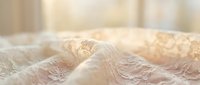 Delicate ivory lace fabric with intricate floral patterns and textured details, suitable for wedding gowns, bridal wear, formal apparel design, and luxury textile applications.