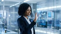 Young African American woman in professional business attire interacting with digital holographic display in modern office environment, representing technology innovation and corporate solutions.
