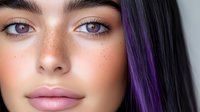 Young woman with freckles, natural makeup, and purple hair streak closeup portrait showing fresh glowing skin, plump pink lips, and expressive eyes.