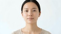 Young East Asian woman with straight black hair, neutral expression, wearing casual beige t-shirt against white background. Portrait suitable for diversity, healthcare, education, and corporate communications.