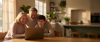 Happy Caucasian family with teenage son using laptop together at home kitchen table, parents helping child with homework or online learning activities.