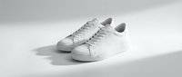 Pair of clean white leather sneakers on a light gray background, showcasing minimalist style and casual elegance for fashion and lifestyle use.