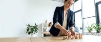 Young male professional of South Asian descent in business casual attire arranging wooden blocks on desk, symbolizing strategic planning, risk management, and corporate growth for business concepts.