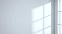 Bright window casting geometric shadows on white wall, creating minimalist interior lighting effect for modern design projects.