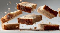 Fresh baked bread slices floating in air with crumbs scattered around on white background. Artisan bakery product for food photography and culinary designs.