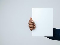 Cropped hand of male with medium skin tone holding blank white card against neutral background, suitable for advertising, marketing campaigns, and promotional materials.