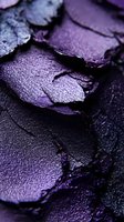 Crushed purple eyeshadow macro texture showing shimmering metallic powder and broken pieces. Rich dark violet cosmetic product close-up for beauty and makeup artistry.