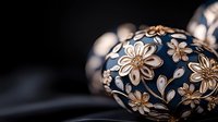 Decorative Easter egg with delicate floral pattern in navy blue and cream colors against dark background, showcasing intricate handcrafted details and traditional design.