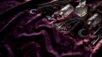 Dark purple velvet fabric with ornate silver jewelry including chains, pendants and decorative accessories creating luxurious gothic aesthetic composition.