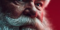 Close-up portrait of senior man with white beard against red background, showing facial details and wrinkles that convey wisdom and life experience.