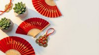 Chinese New Year celebration with red folding fans, jade ornaments and succulents on beige background for festive holiday decorations and cultural events.