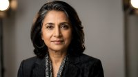 Professional middle-aged South Asian businesswoman in dark suit jacket with confident expression in modern office setting for corporate presentations.