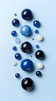 Glossy blue and black spheres with white accents arranged on light blue background, creating elegant composition for cosmetic or jewelry design.