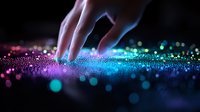 Fingers touching glowing sparkles on dark surface with vibrant pink and blue bokeh lights creating magical atmosphere. Artistic macro photography for fantasy designs.