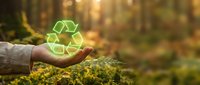 Hand holding glowing green recycling symbol in forest setting with warm sunlight, representing environmental conservation and sustainable living practices.