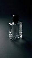 Empty crystal perfume bottle with black cap on dark background, isolated for cosmetics, fragrance, and luxury product design use.