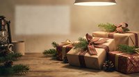 Wrapped Christmas gifts with brown paper and plaid ribbons arranged on rustic wooden table with evergreen branches and warm lighting for holiday celebrations.