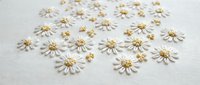 Delicate white daisy flowers with golden centers scattered on neutral background for crafting, scrapbooking and decorative design projects.