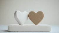 White and brown heart shapes on minimal white platform against neutral background, symbolizing unity, relationship and love concept for romantic designs.