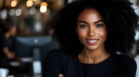 Young African American woman with natural curly hair and bright smile wearing black top, arms crossed, against blurred cafe background with warm bokeh lights.