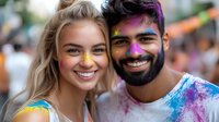 Young diverse couple smiling at festival, covered in colorful holi powder paint with vibrant purple and yellow colors against blurred festive background.