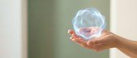 Hand holding translucent soap bubble with pink liquid inside against blurred background. Suitable for wellness, cleanliness, and skincare marketing materials.