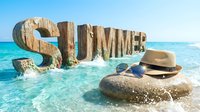 Wooden SUMMER letters standing in turquoise ocean waves with straw hat and sunglasses on rock, sunny beach vacation concept.