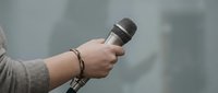 Professional journalist holding microphone during live news report or interview session for media broadcasting and communication purposes.