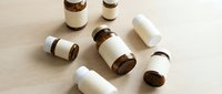 Essential oil bottles with blank labels scattered on wooden surface for aromatherapy and natural wellness branding mockup design projects.
