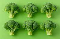 Fresh raw broccoli florets arranged in two rows on green background. Healthy vegetable pattern layout showing natural organic produce for nutrition concept.
