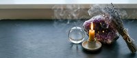 Dried lavender bouquet with burning candle and magnifying glass on dark wooden table creating cozy aromatherapy atmosphere for relaxation and wellness.