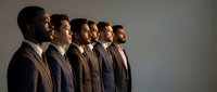 Professional businessmen in suits standing in profile formation against neutral background for corporate leadership concepts.