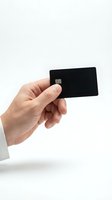 Hand holding black credit card with chip on white background for financial and payment concepts.