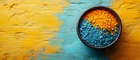 Vibrant blue and yellow spices in ceramic bowl on textured yellow and turquoise background, top view with copy space for food photography and menu design.