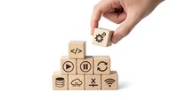 Hand placing wooden cube with gear icon on pyramid of technology symbol blocks isolated on white background for business and digital concepts.