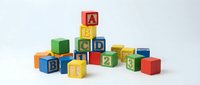 Colorful wooden alphabet blocks with letters and numbers scattered on white background, educational toys for children learning and development.
