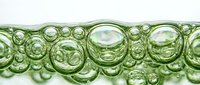 Green translucent bubbles floating in liquid creating abstract pattern with iridescent reflections and organic shapes for modern design backgrounds.