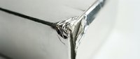 Shiny metallic silver foil wrapping paper corner with crumpled texture and reflective surface for packaging and gift decoration projects.