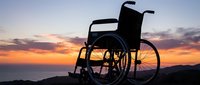 Empty wheelchair silhouette against dramatic sunset sky, symbolizing disability awareness, accessibility, rehabilitation, and inclusive healthcare concepts for medical and social campaigns.