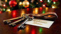 Vintage brass keys with a welcome home tag on a wooden table, festive Christmas tree lights glowing in the background, new home gift concept.
