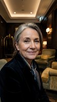 Confident mature businesswoman with gray hair smiling in luxury hotel lobby wearing dark blazer for corporate hospitality and professional services.