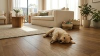 Golden retriever puppy resting on warm hardwood floor in bright Scandinavian-style living room with neutral tones and natural light.