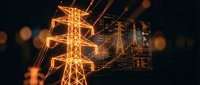 Electric power transmission tower with glowing orange circuit board overlay representing smart grid technology and digital energy infrastructure innovation.