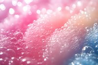 Dreamy pink and blue bokeh background with sparkling water droplets and soft focus bubbles creates magical ethereal atmosphere for romantic designs.